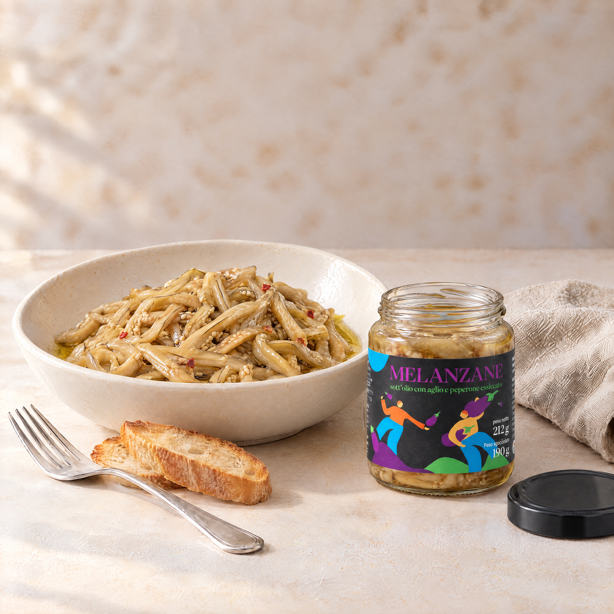 Antipasto di melanzane a filetto sott’olio Minnelea, con pane e vasetto aperto.