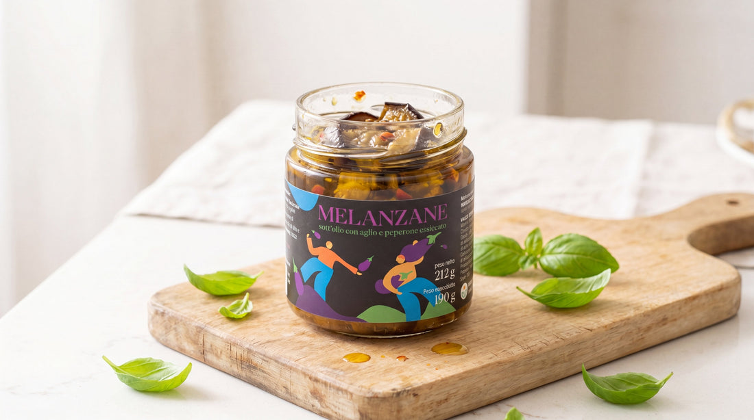 Vasetto aperto di melanzane sott'olio su tagliere di legno chiaro con foglie di basilico