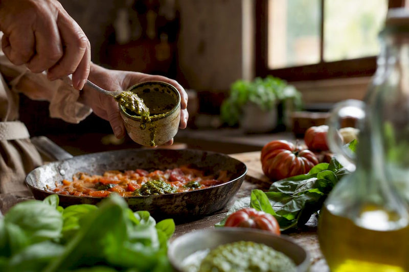 In einer gemütlichen Landhausküche schöpft jemand von Hand eine liebevoll zubereitete Tomatensauce.
