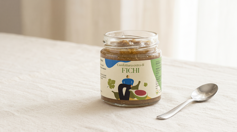 Vasetto aperto di confettura extra di fichi Minnelea con l'etichetta e la percentuale di frutta ben visibili, accanto a un cucchiaino pulito