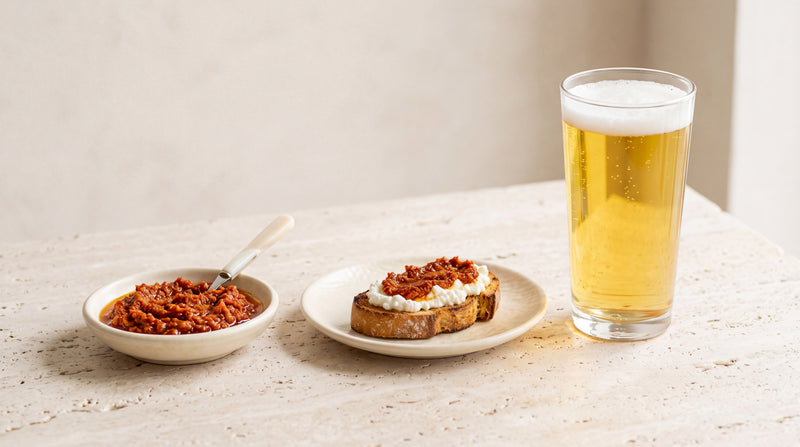 Lager chiara nel bicchiere, paté di pomodori secchi e crostino di ricotta