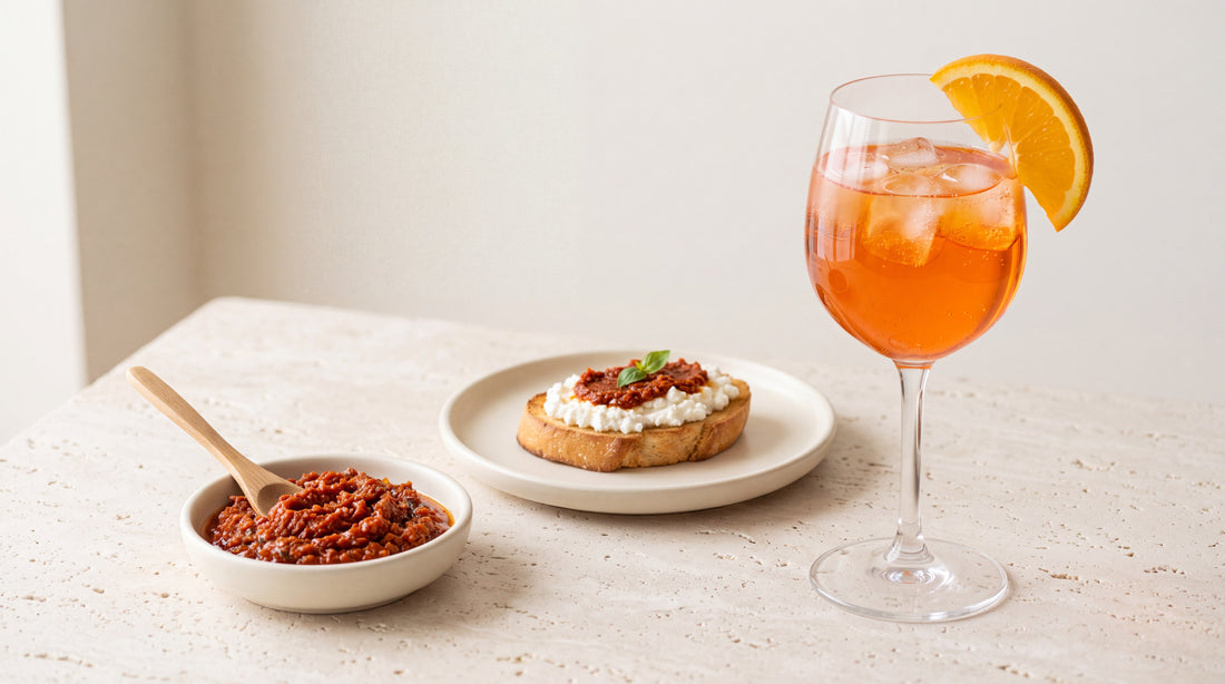 Spritz arancione con ghiaccio, paté di pomodori secchi e crostino di ricotta