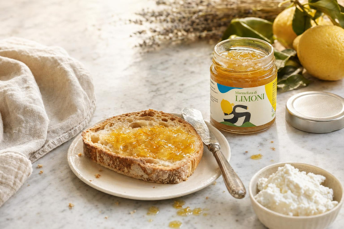 Marmellata Extra di Limoni Minnelea su tavola in marmo Carrara con toast di pane tostato, ricotta fresca, limoni e burro — composizione editoriale per colazione gourmet