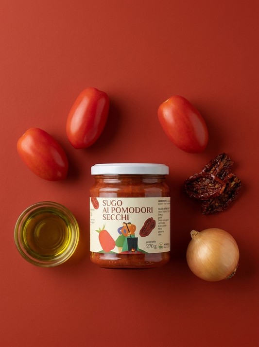 Sugo ai Pomodori Secchi Minnelea - vasetto su fondo rosso circondato dagli ingredienti